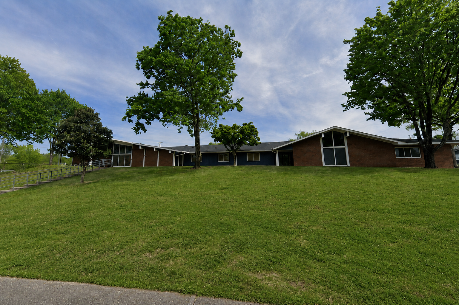 Grassy lawn with mature trees beside a single-story building