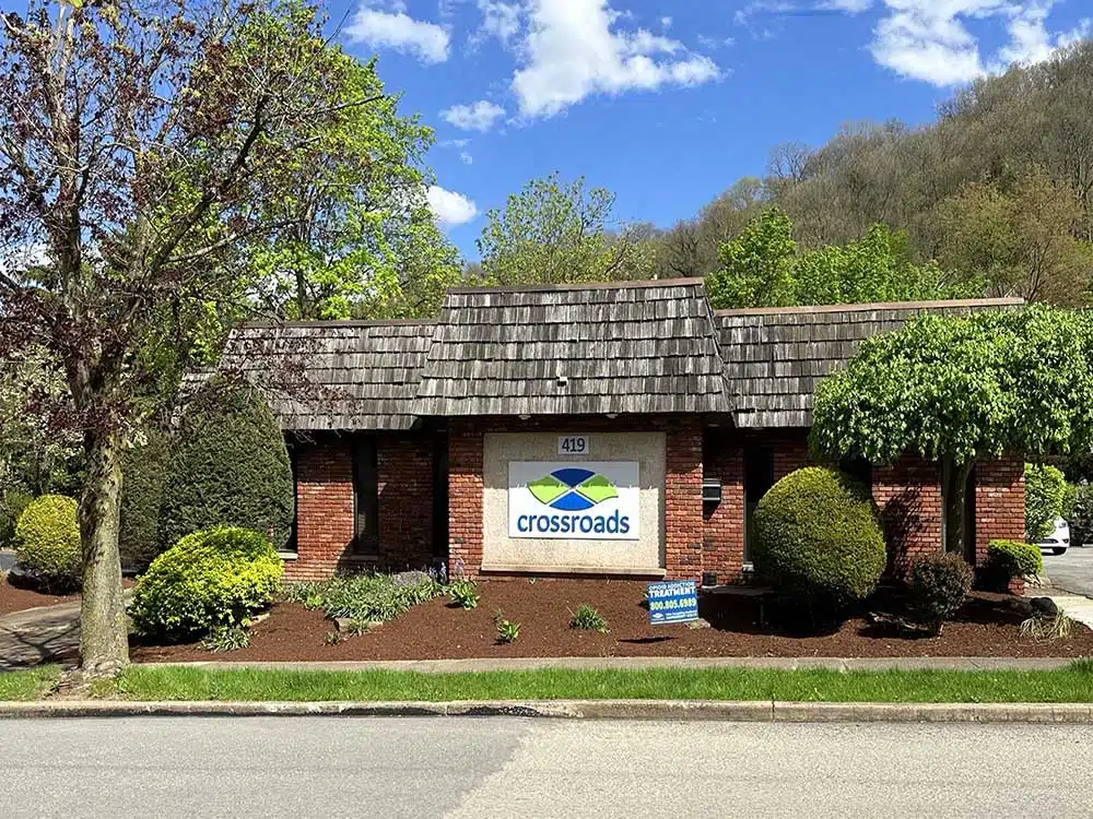 Crossroads sign on brick building with trees and shrubs