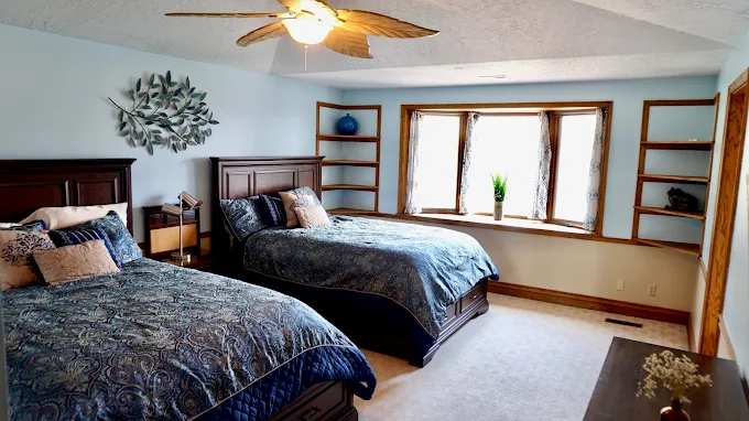 Blue-themed bedroom with two beds and bay window nook