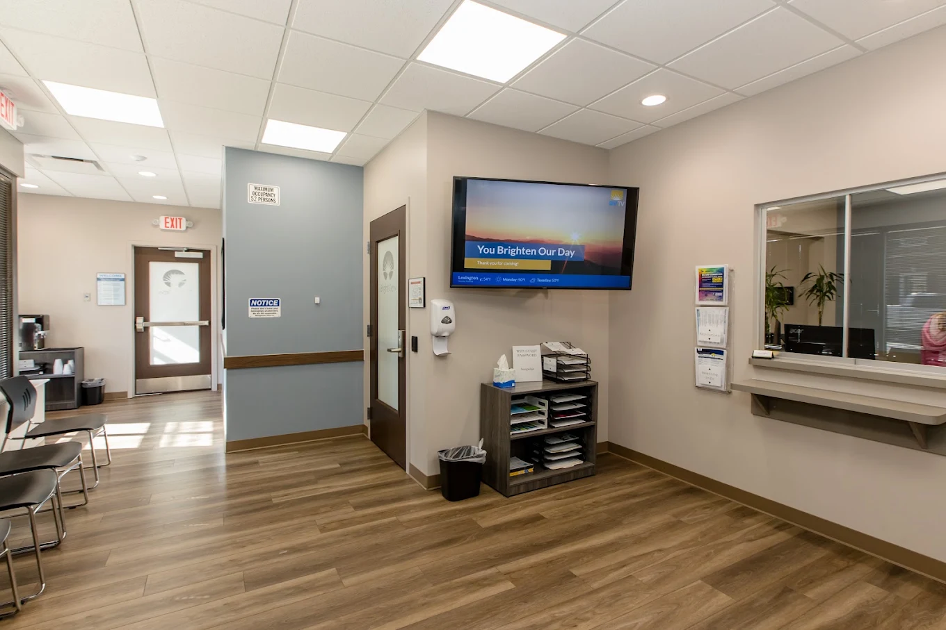 Main lobby with reception window, chairs, and wall-mounted TV