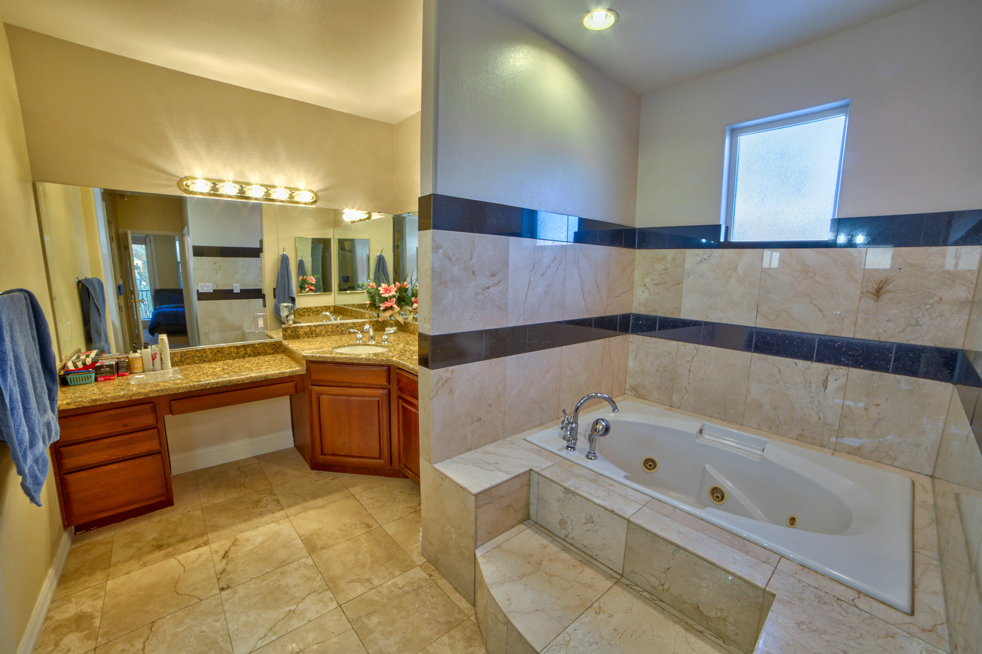 Bathroom with a jacuzzi tub, dual sinks, and cabinetry.