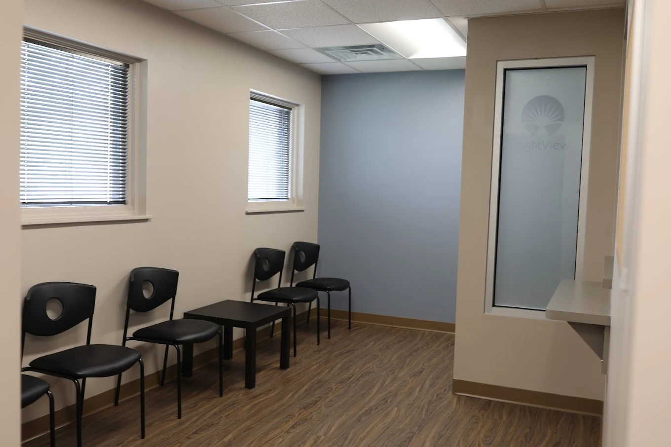 Waiting area with black chairs, tables, and windows