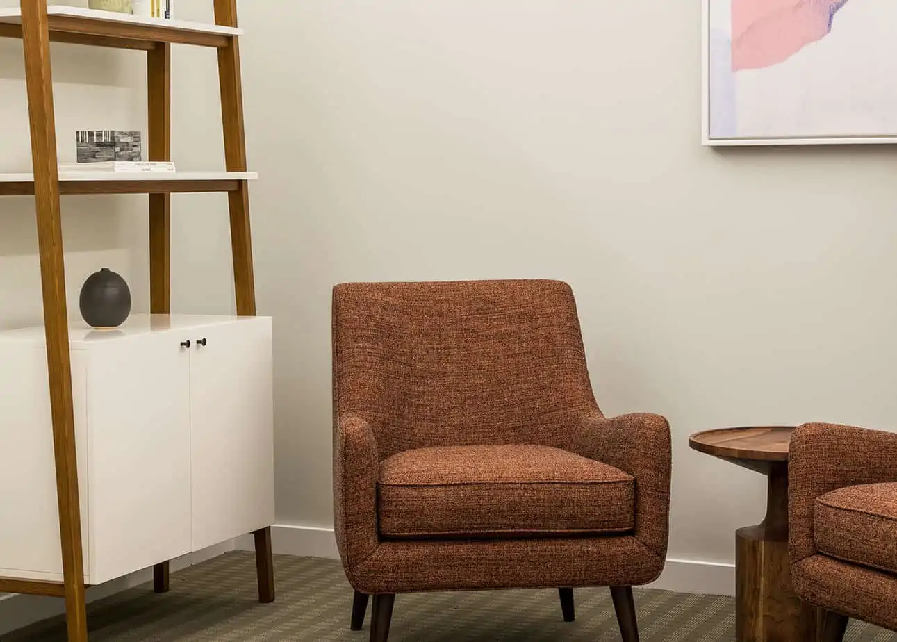 Orange fabric chairs near wooden shelf and table