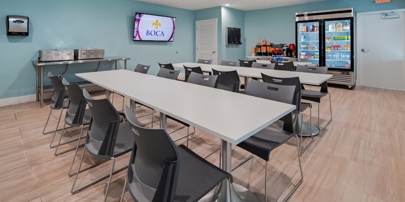 A clean and modern dining area with comfortable seating, a large TV, well-stocked drink coolers, and snack options, creating a welcoming atmosphere.