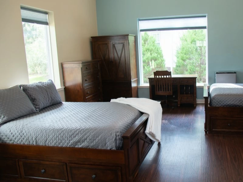 Bedroom with bed, desk, and large windows