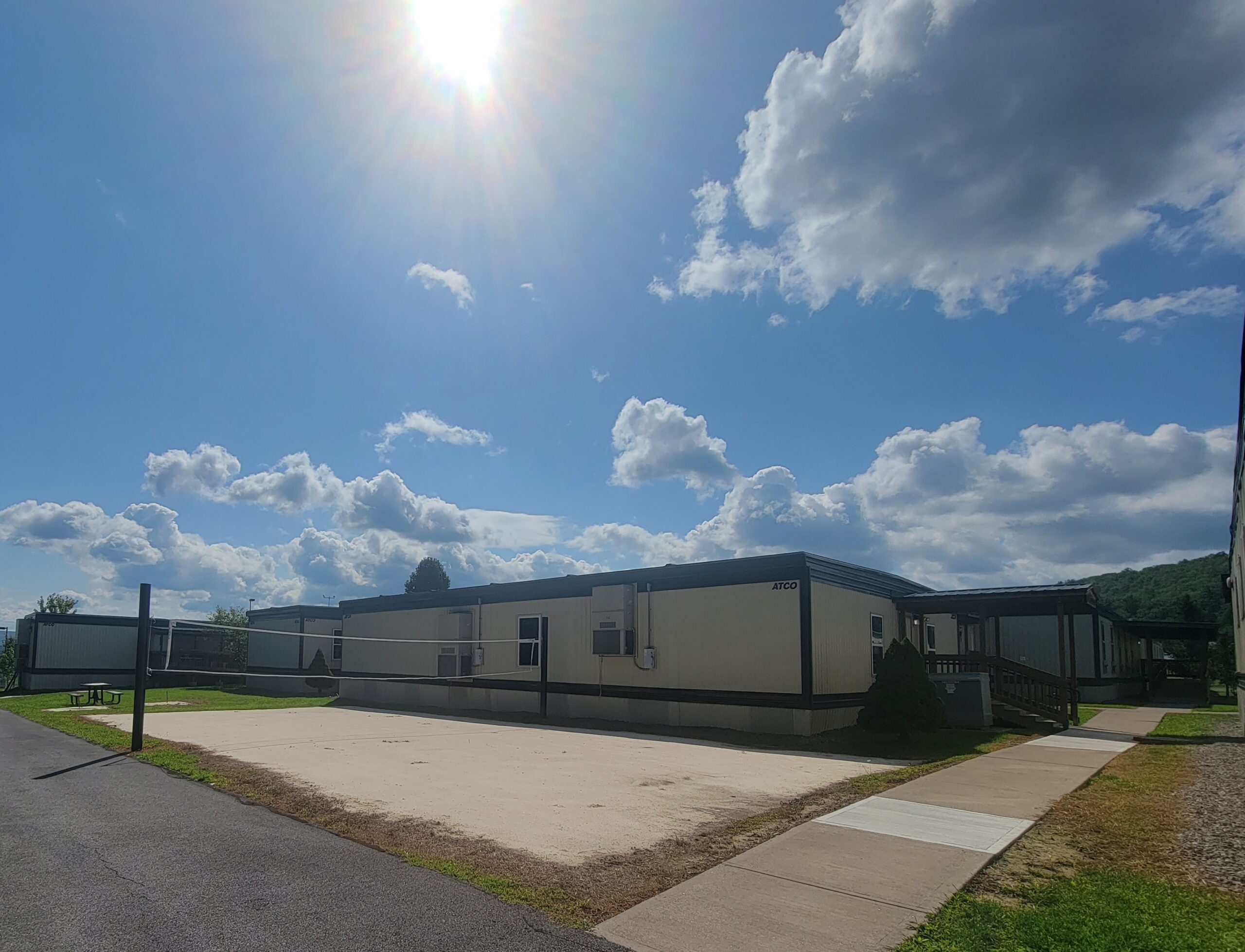 Volleyball court beside modular buildings under sunny sky