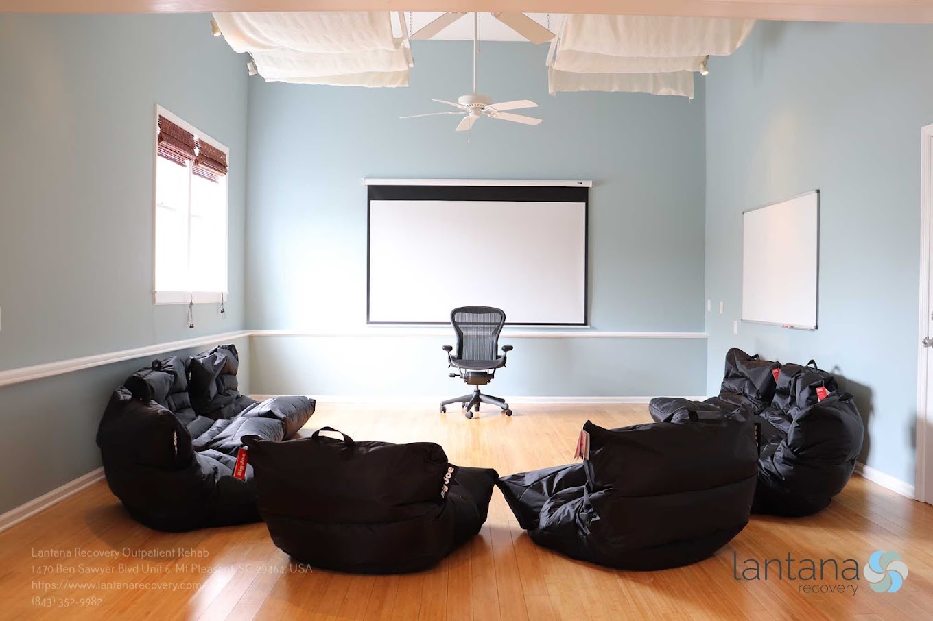 Therapy room with black bean bag chairs and a projector screen.