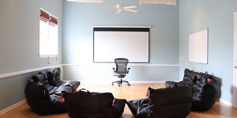 Bright, airy group room with cozy bean bags, a large screen, and a comfortable chair, creating a relaxed and inviting setting for sessions.