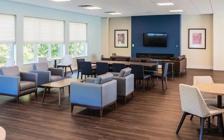 Bright common area with chairs, tables, and large windows
