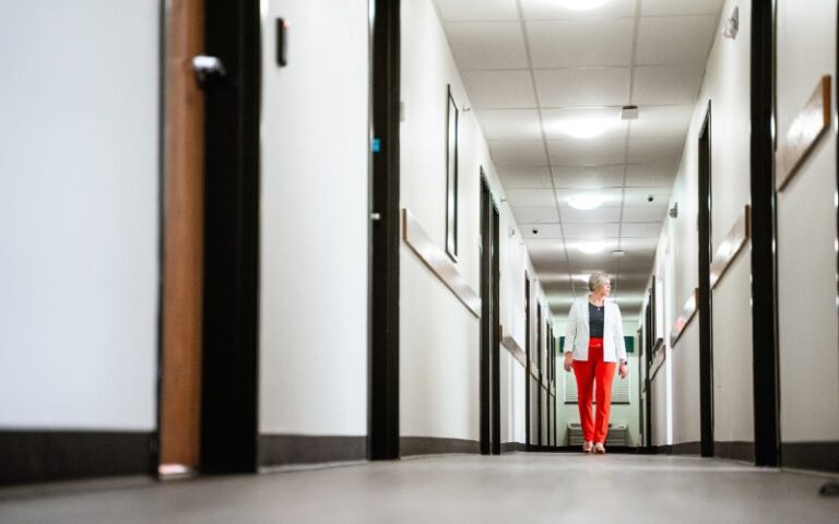 Woman walking down hallway with open doors
