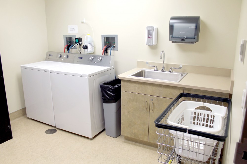 Laundry room with washer, dryer, sink, and laundry cart.