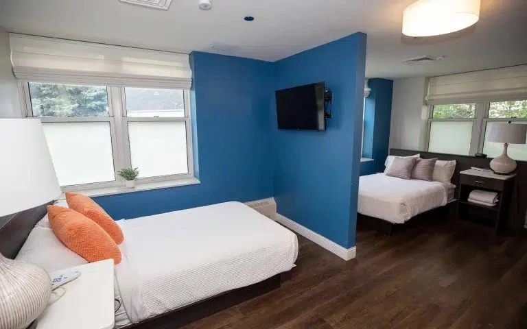 Shared bedroom with two beds, large windows, and television
