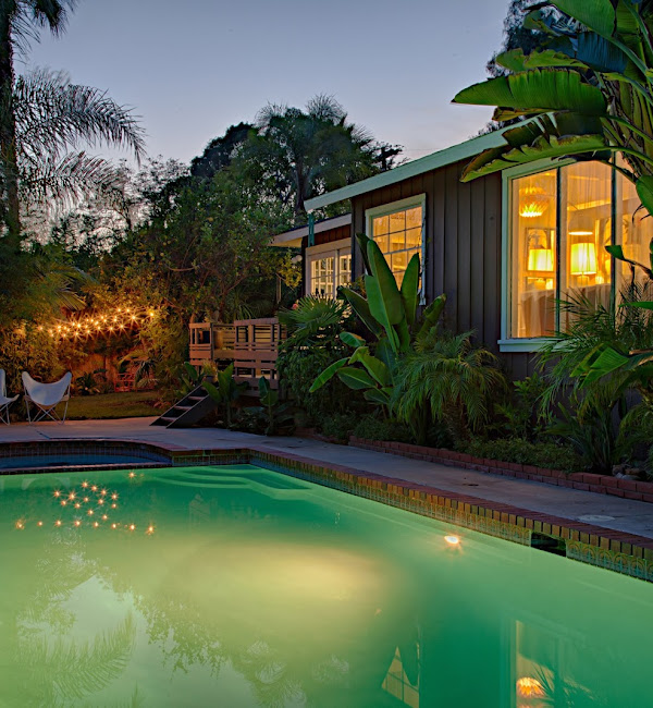 Outdoor pool illuminated beside residential home at dusk
