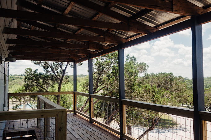 Wooden balcony overlooking trees and driveway