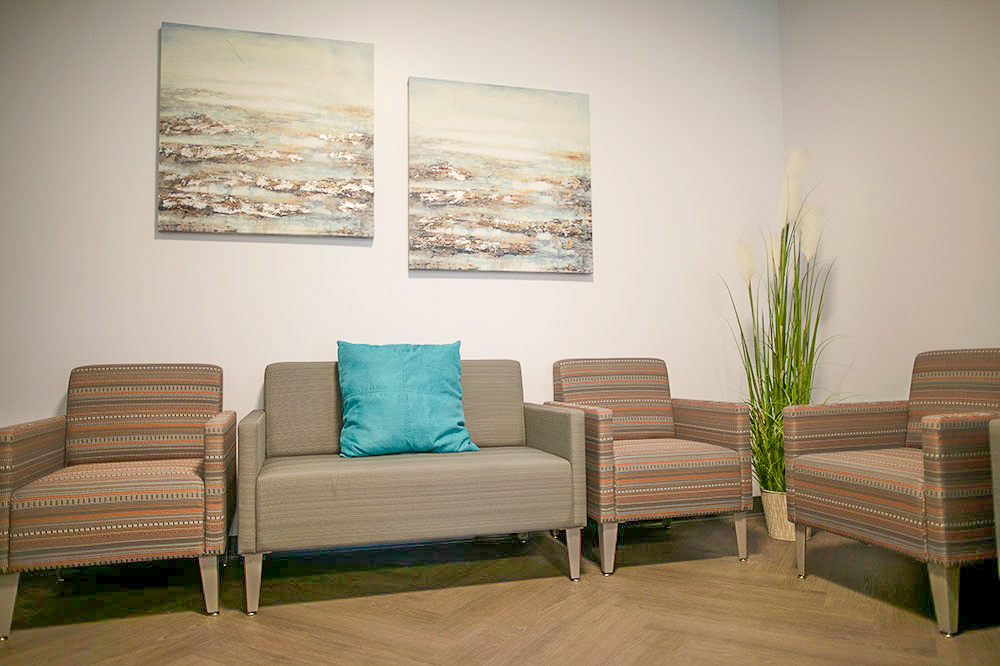 A waiting area with armchairs, a couch, and framed artwork on the wall.
