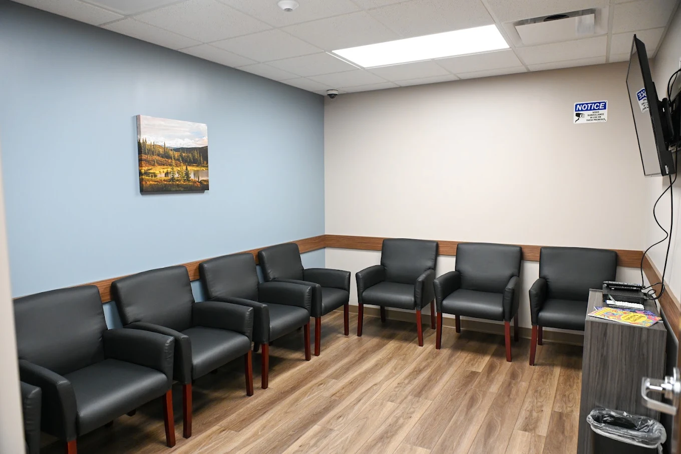 Comfortable patient waiting area with armchairs and TV