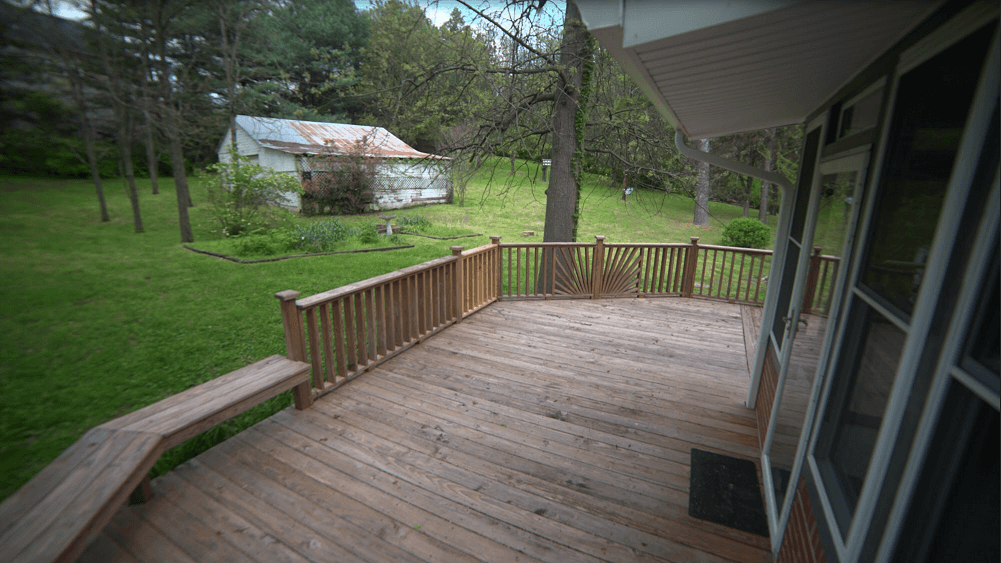 Wooden deck with railing overlooking green yard
