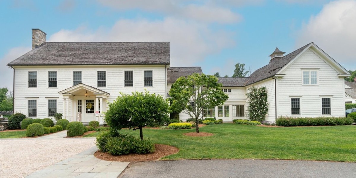 Large white rehab facility with manicured lawn and trees