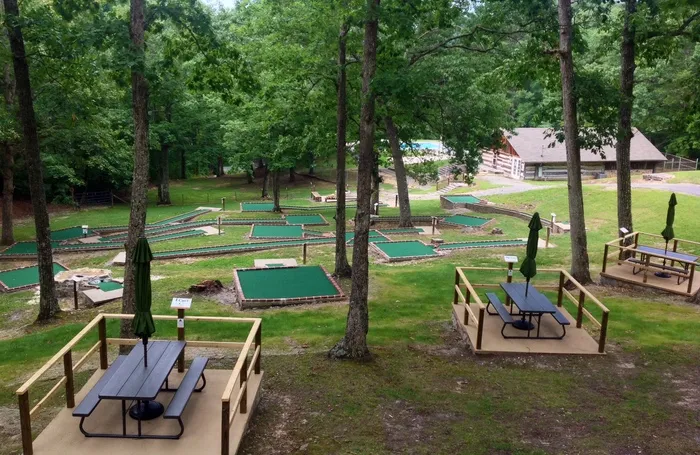 Outdoor recreation area with picnic tables and activity courts among trees