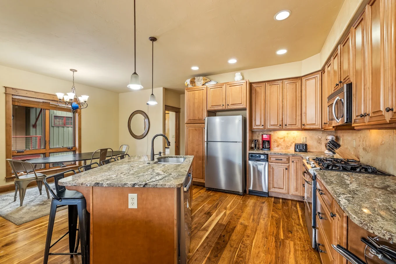 Residential kitchen with wood cabinets, granite island, stainless steel appliances, and adjacent dining area