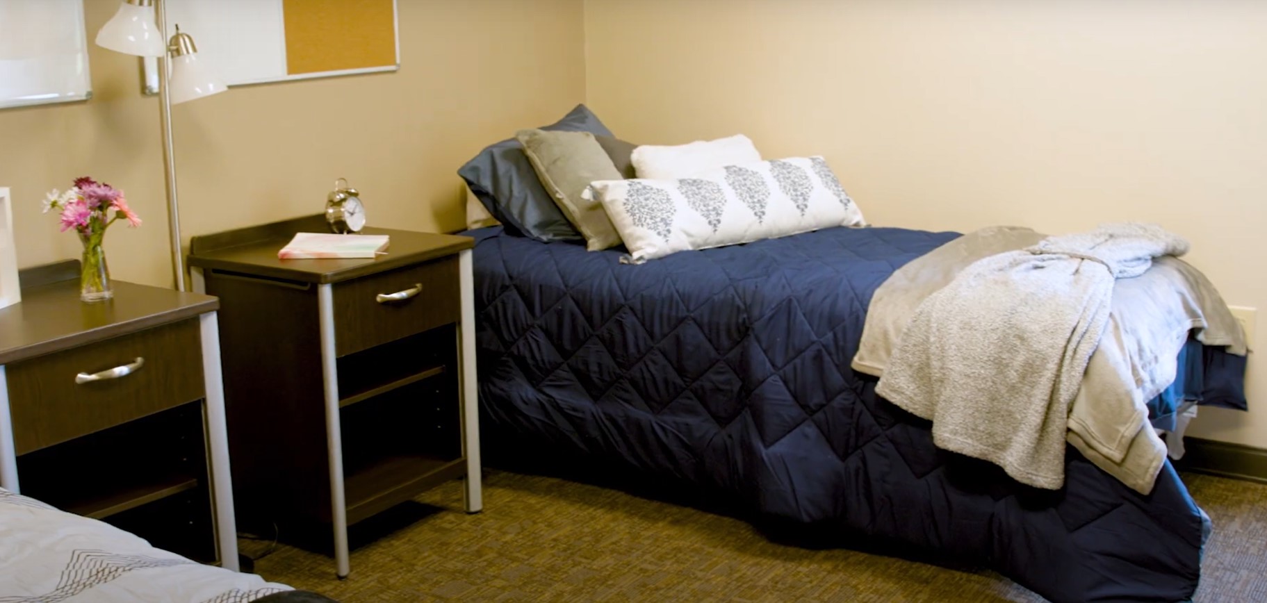 Bed with dark blue bedding and a side table in cozy room