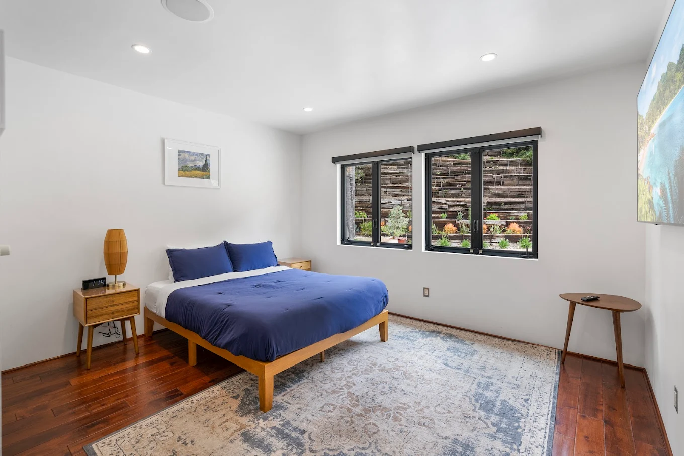 Bedroom with queen bed, wood floors, and garden view