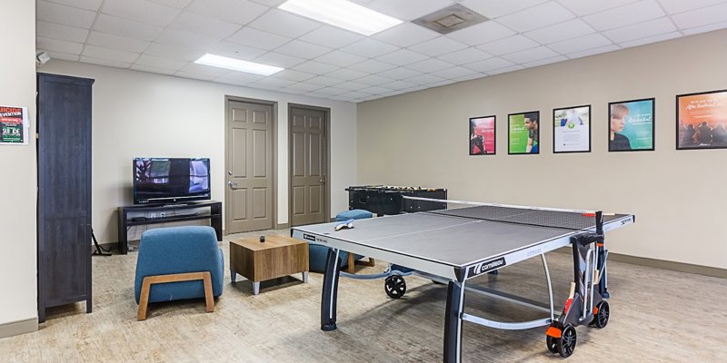 A recreation room with a ping pong table, foosball, and a cozy seating area with a TV, offering a fun and relaxing space for activities.