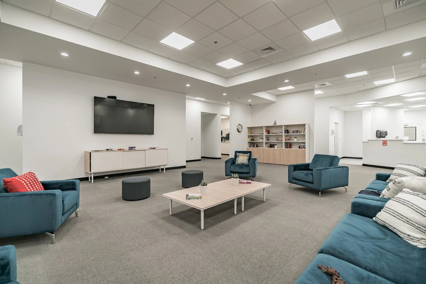 Common lounge with TV, seating, and activity shelves