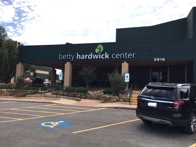 Green building facade with Betty Hardwick Center sign and parking area