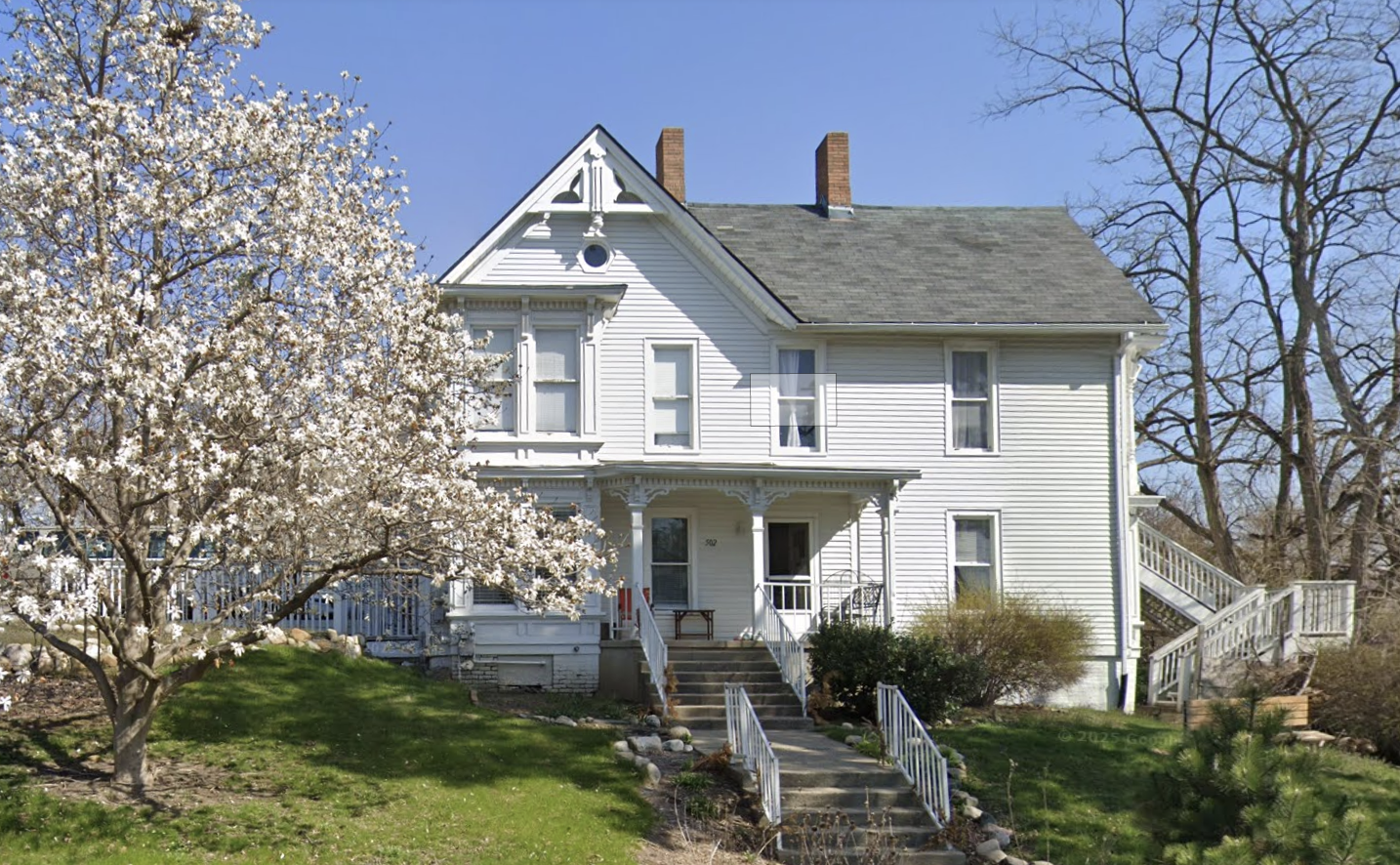 White residential facility surrounded by trees and lawn