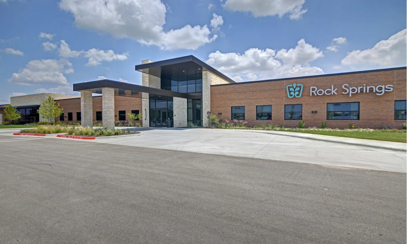 The front exterior of Rock Springs Georgetown with contemporary brick and stone architecture, a covered entrance, and landscaped surroundings