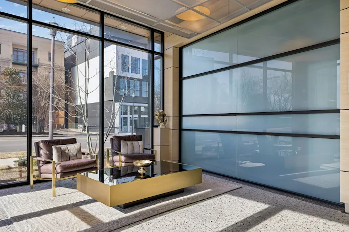Sitting area with leather chairs, gold table, and frosted wall.
