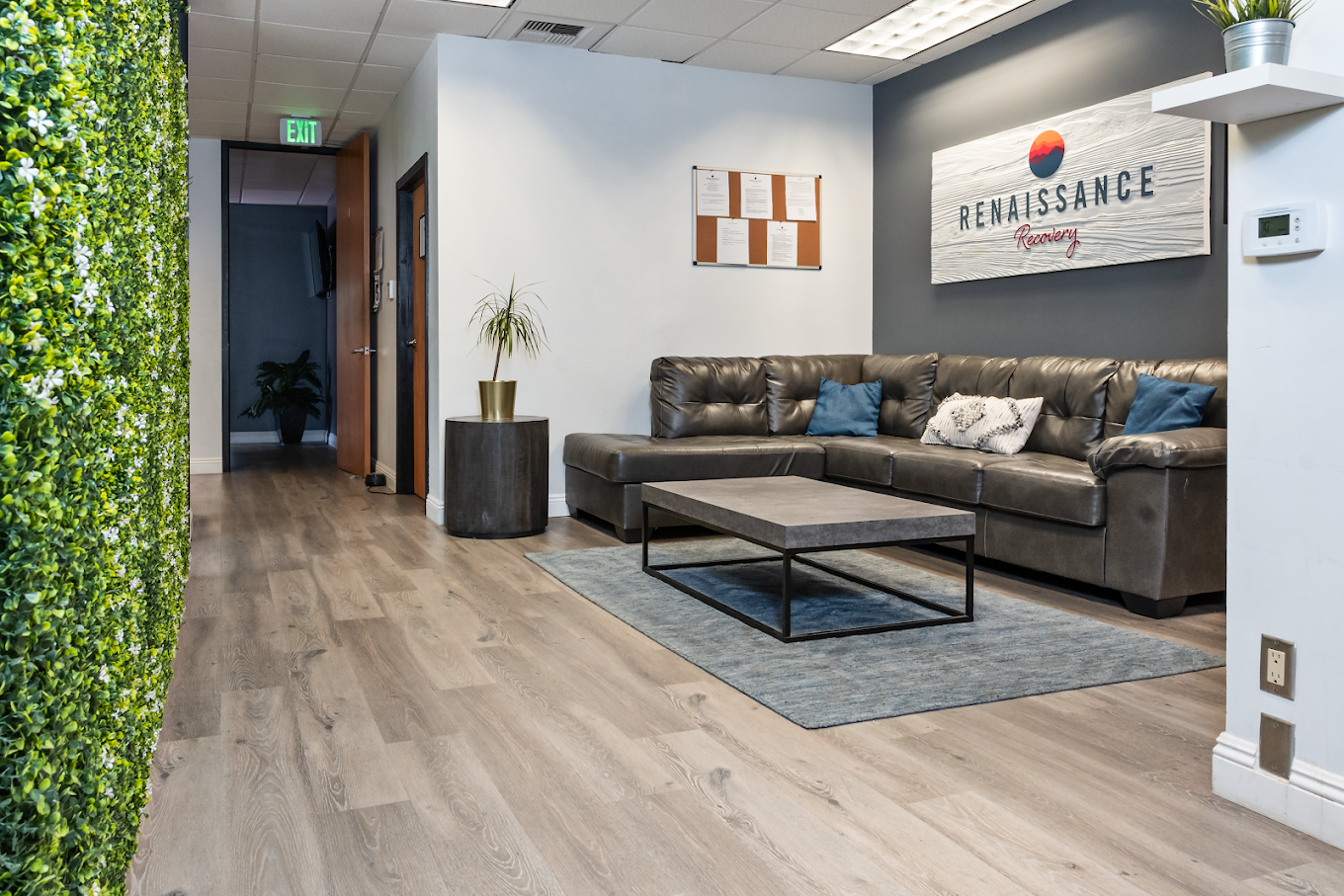 Lounge with gray sectional sofa and greenery wall decor