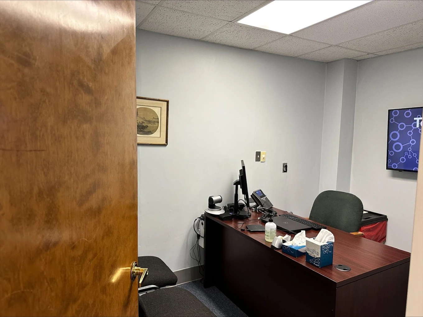 Private consultation room with desk, computer equipment, and visitor seating
