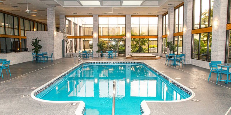 Bright indoor pool area with tall windows, modern seating, and natural light.