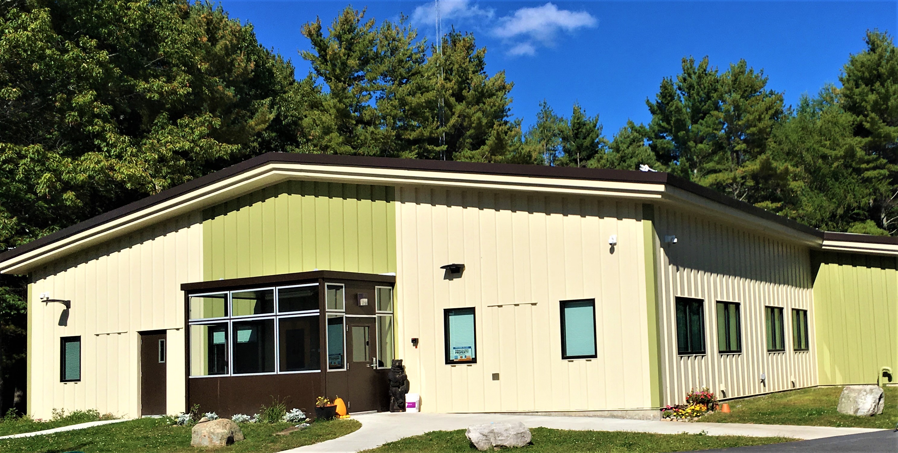 Modern beige and green building of the Champlain Valley Family Center Recovery Campus surrounded by trees