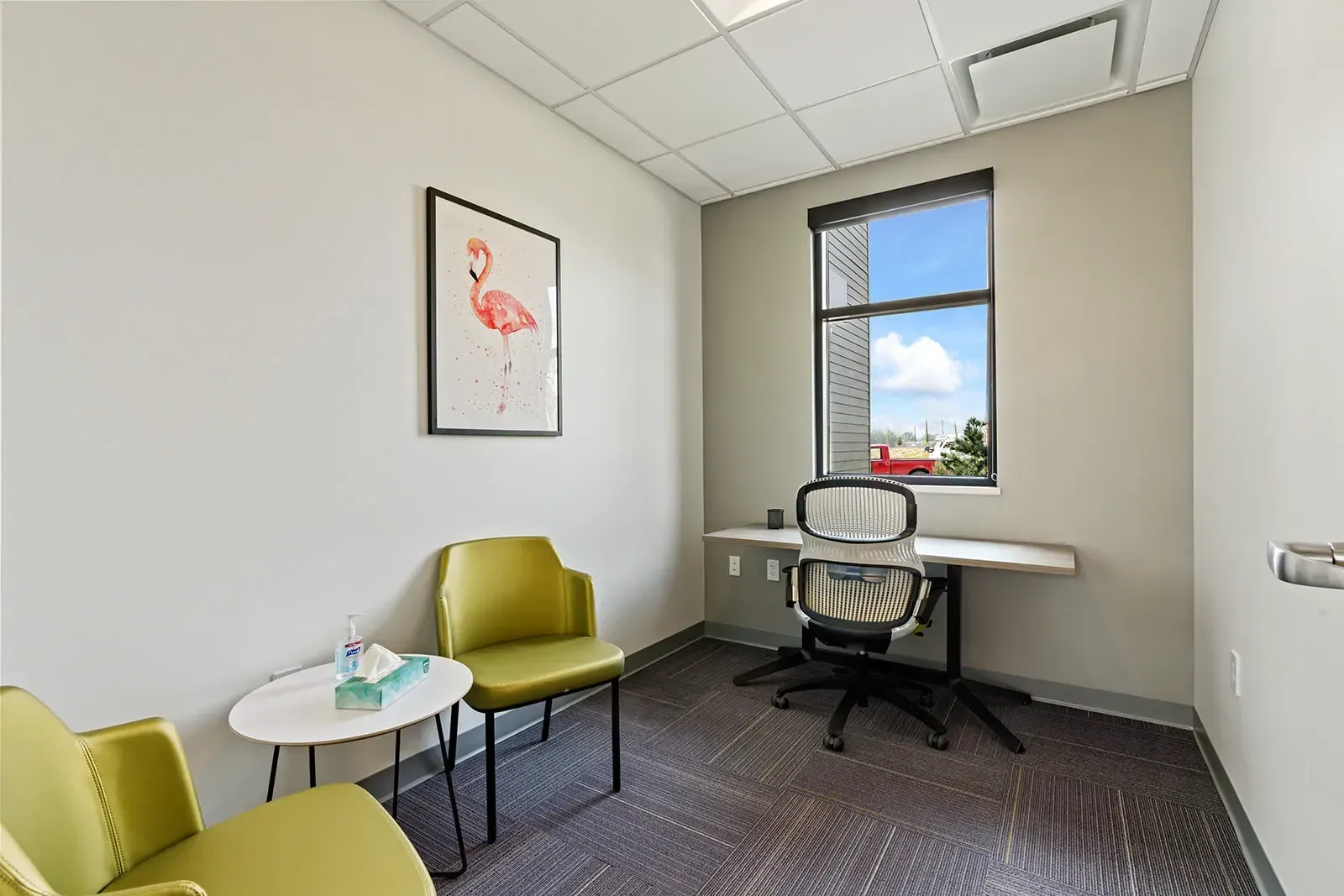 Private therapy room with chairs and desk by window