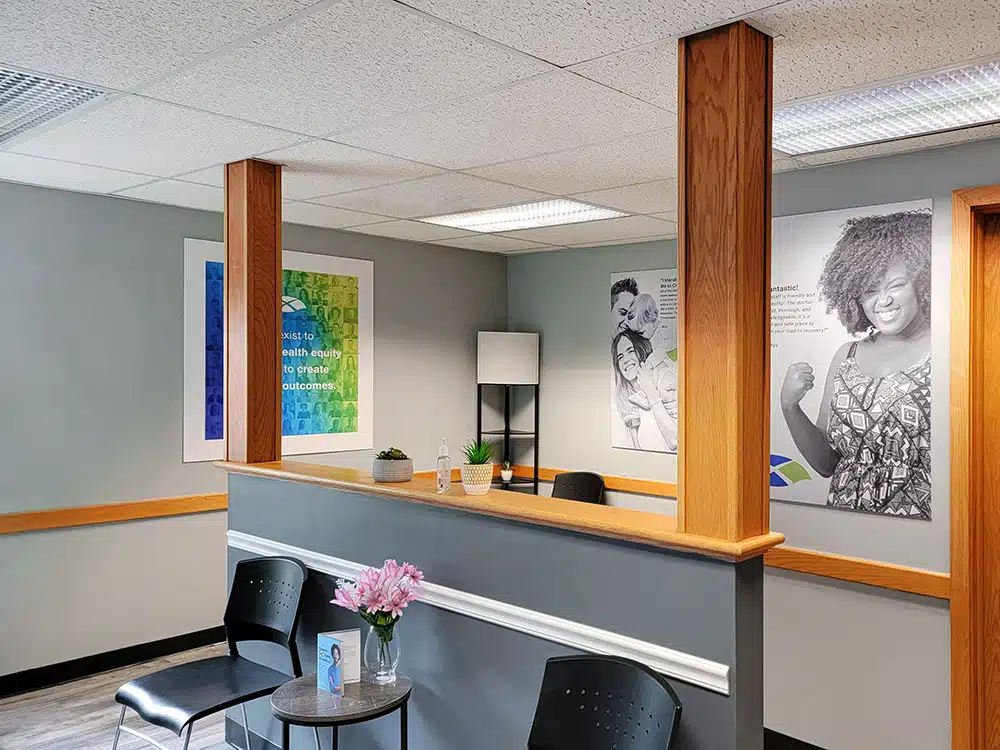 Reception counter with chairs, table, and wall artwork