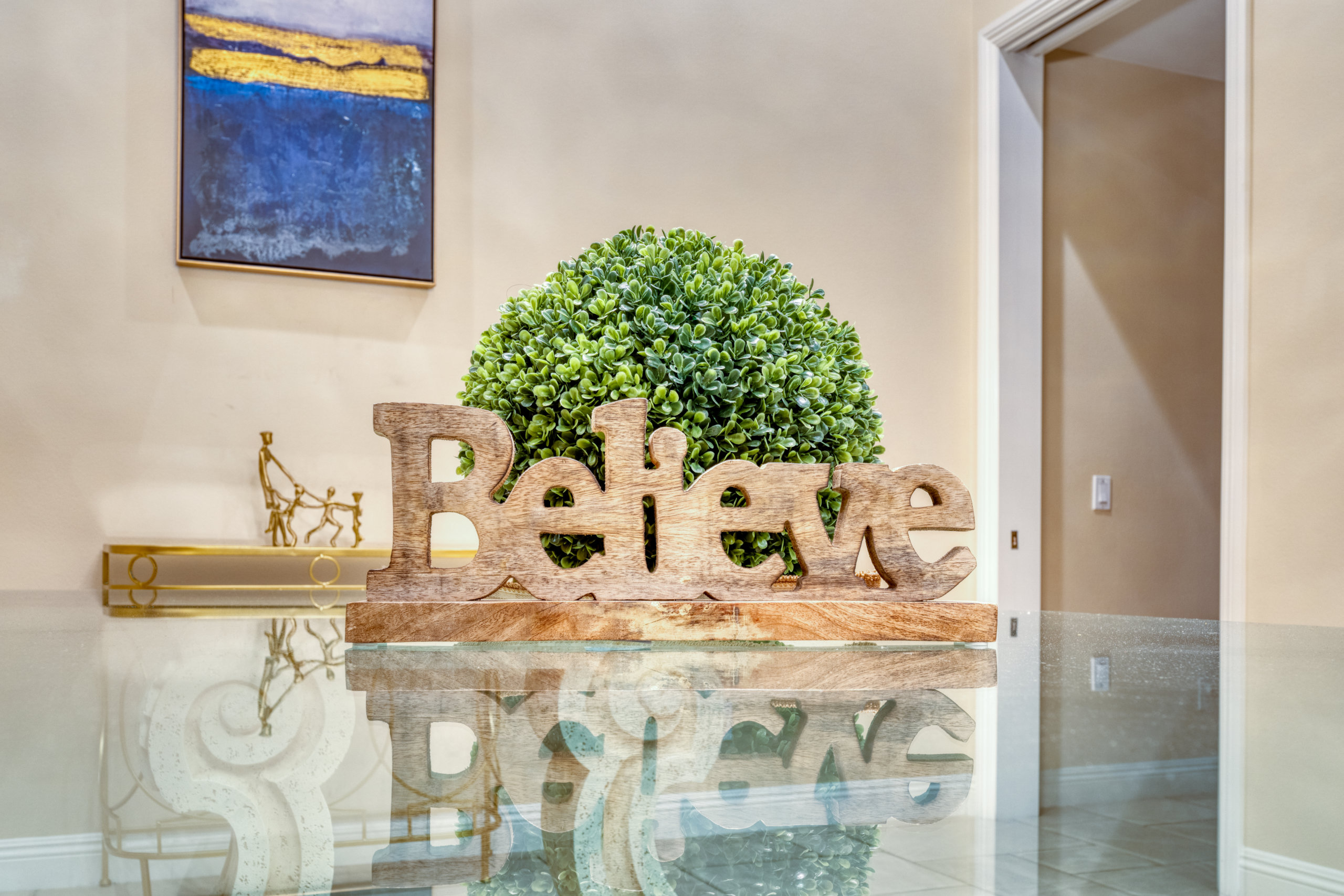 Lobby table with "Believe" sign and green plant centerpiece