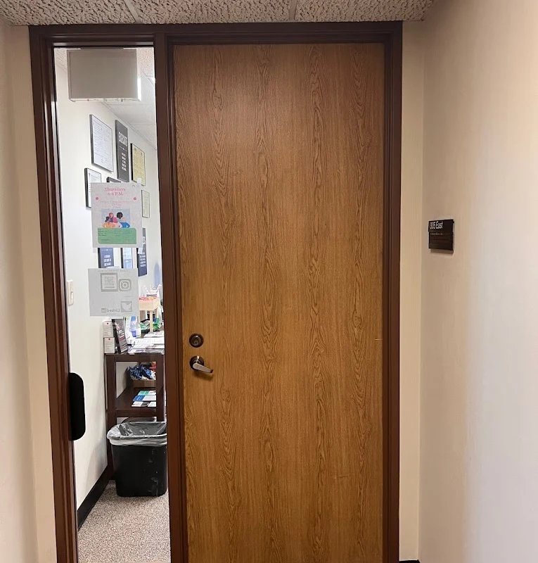 Wooden door with office number and a partial view inside