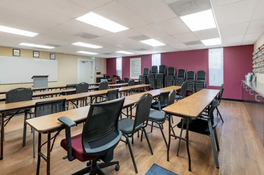 Classroom with tables, chairs, and stacked seating in back