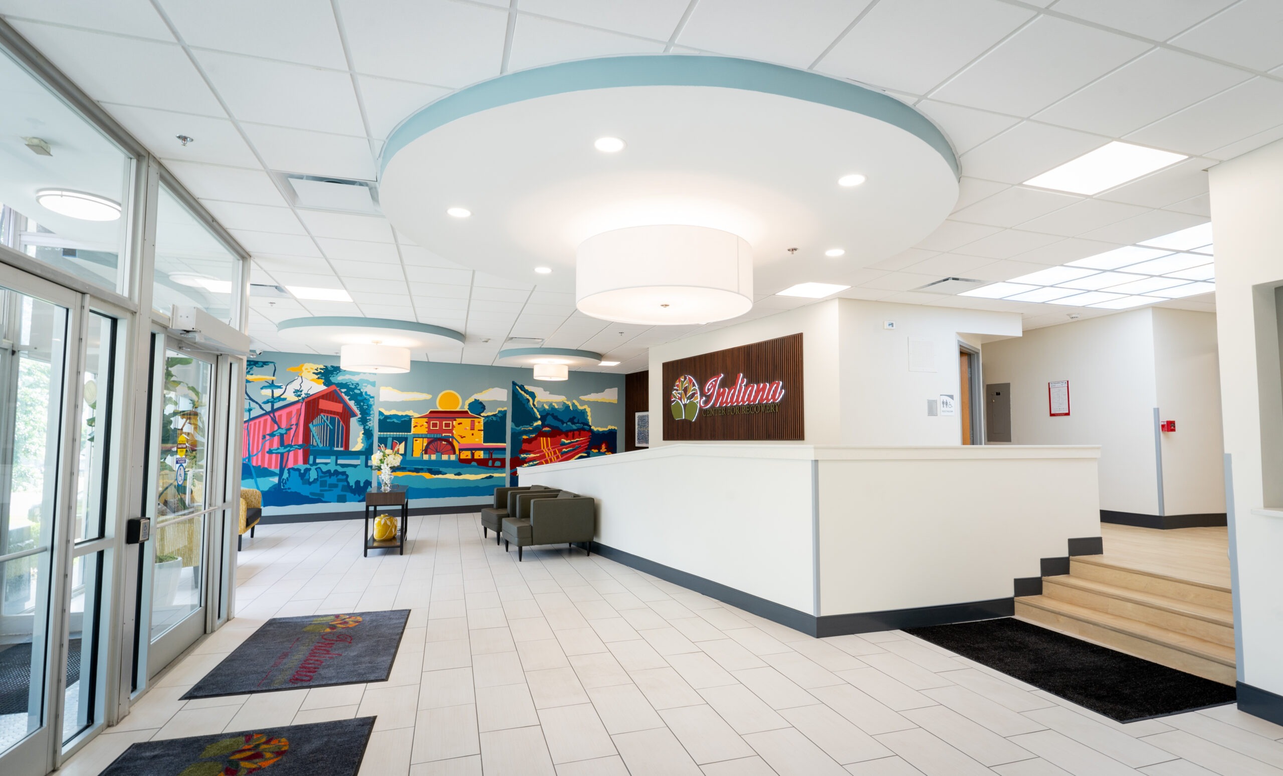 Bright lobby with seating and colorful mural near reception desk.