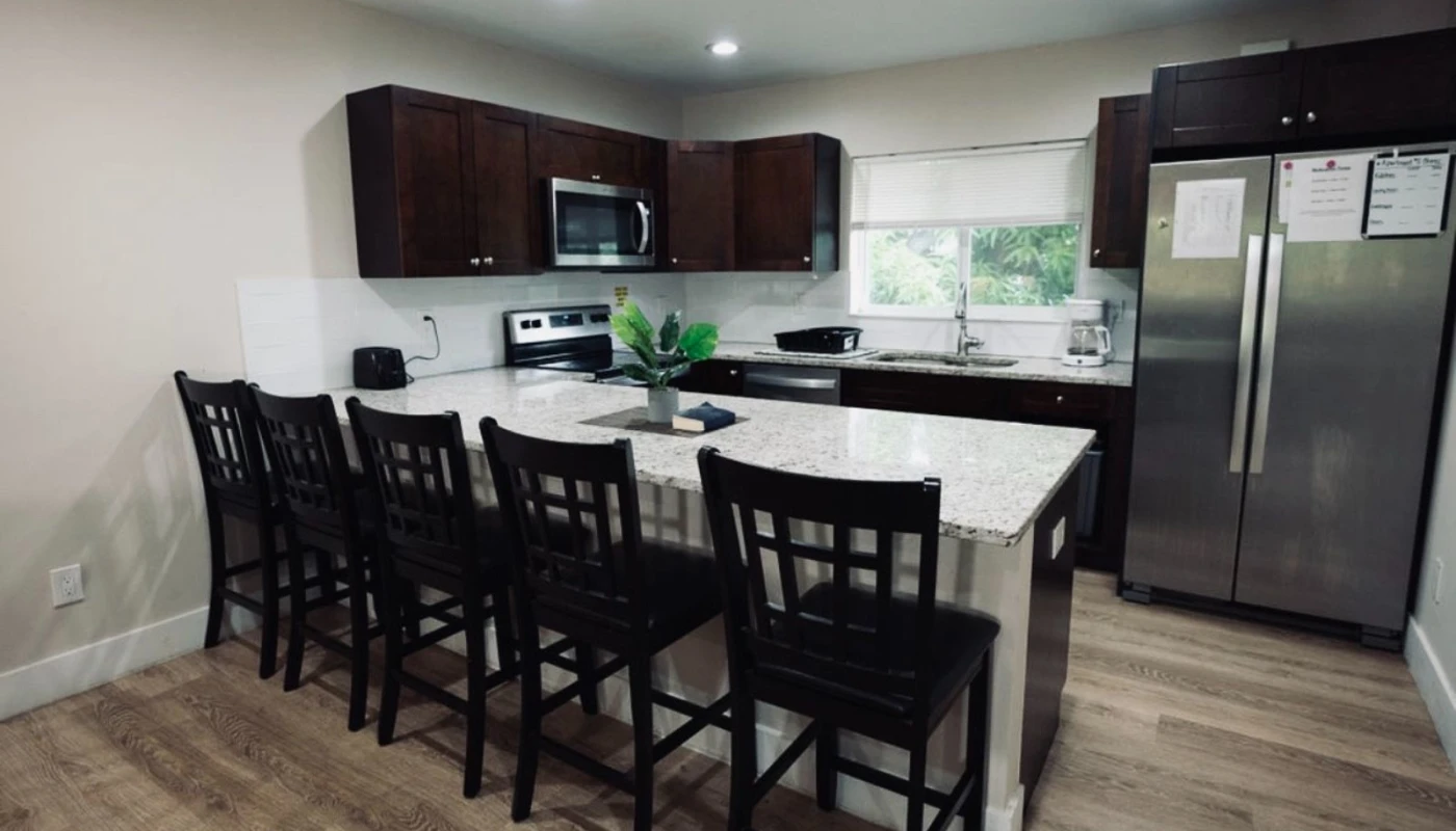 Spacious residential kitchen with granite countertops and bar seating.