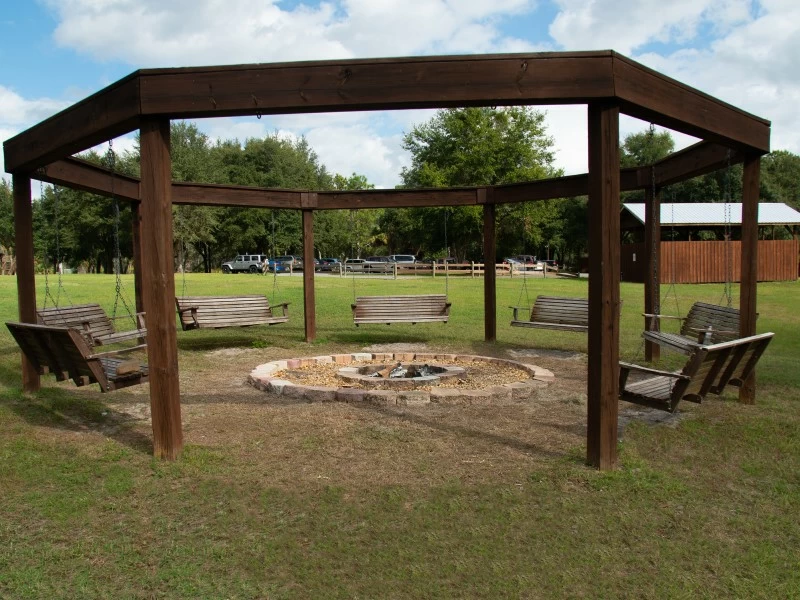 Wooden swings around fire pit in grassy outdoor area