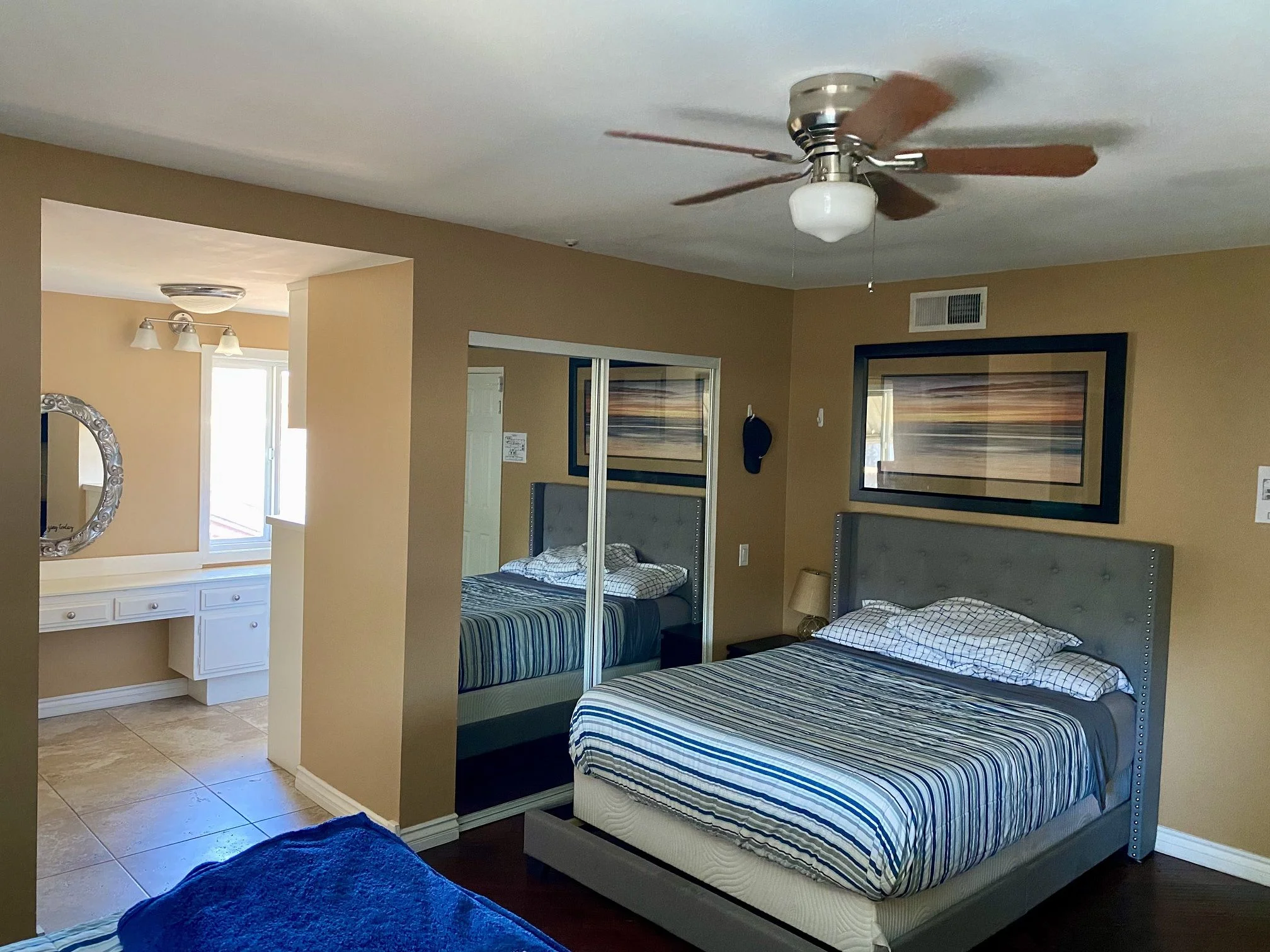 Bedroom with striped bedding and mirrored closet