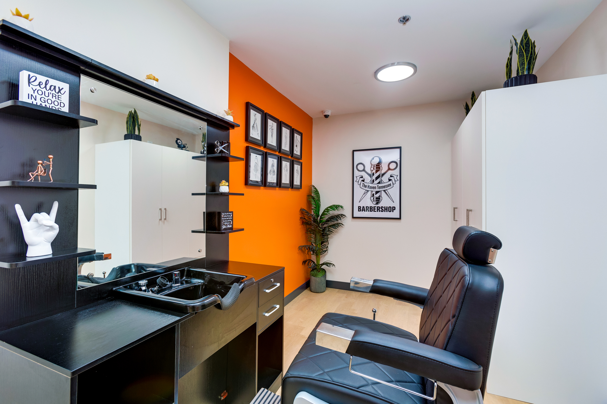 Salon station with a black chair, sink, and wall mirror