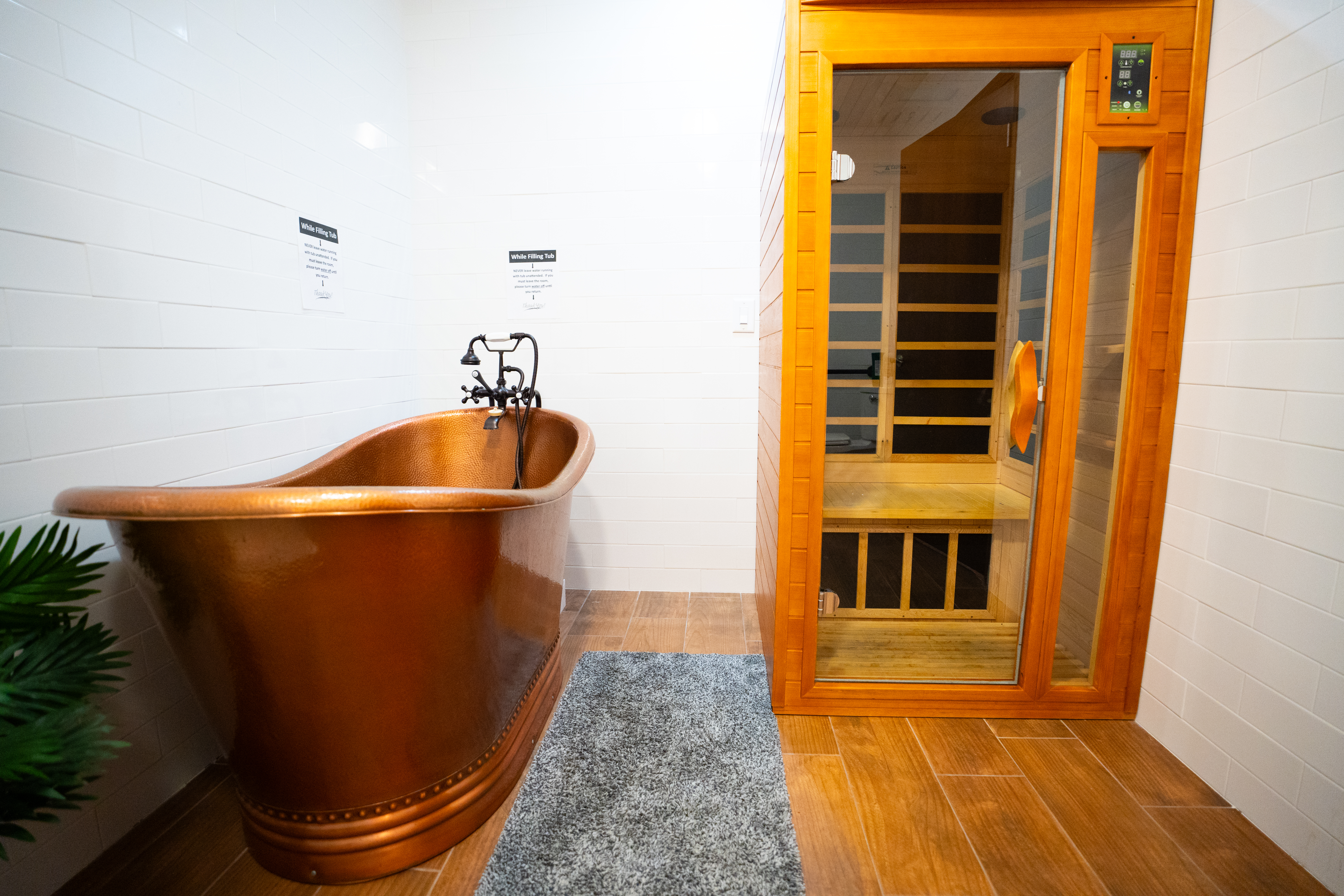 A copper bathtub next to a sauna in a spa-like setting.