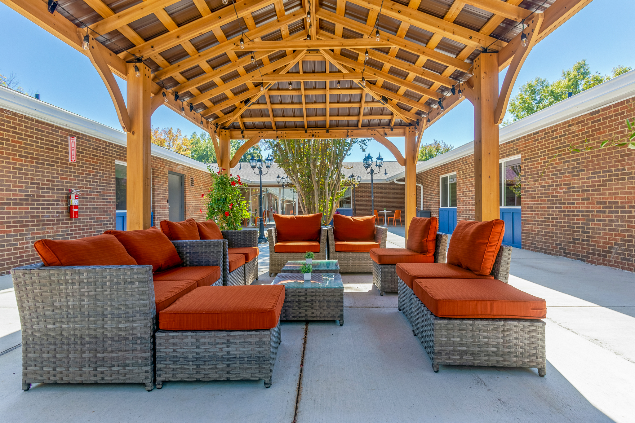 Covered patio with orange-cushioned sofas and a wooden roof