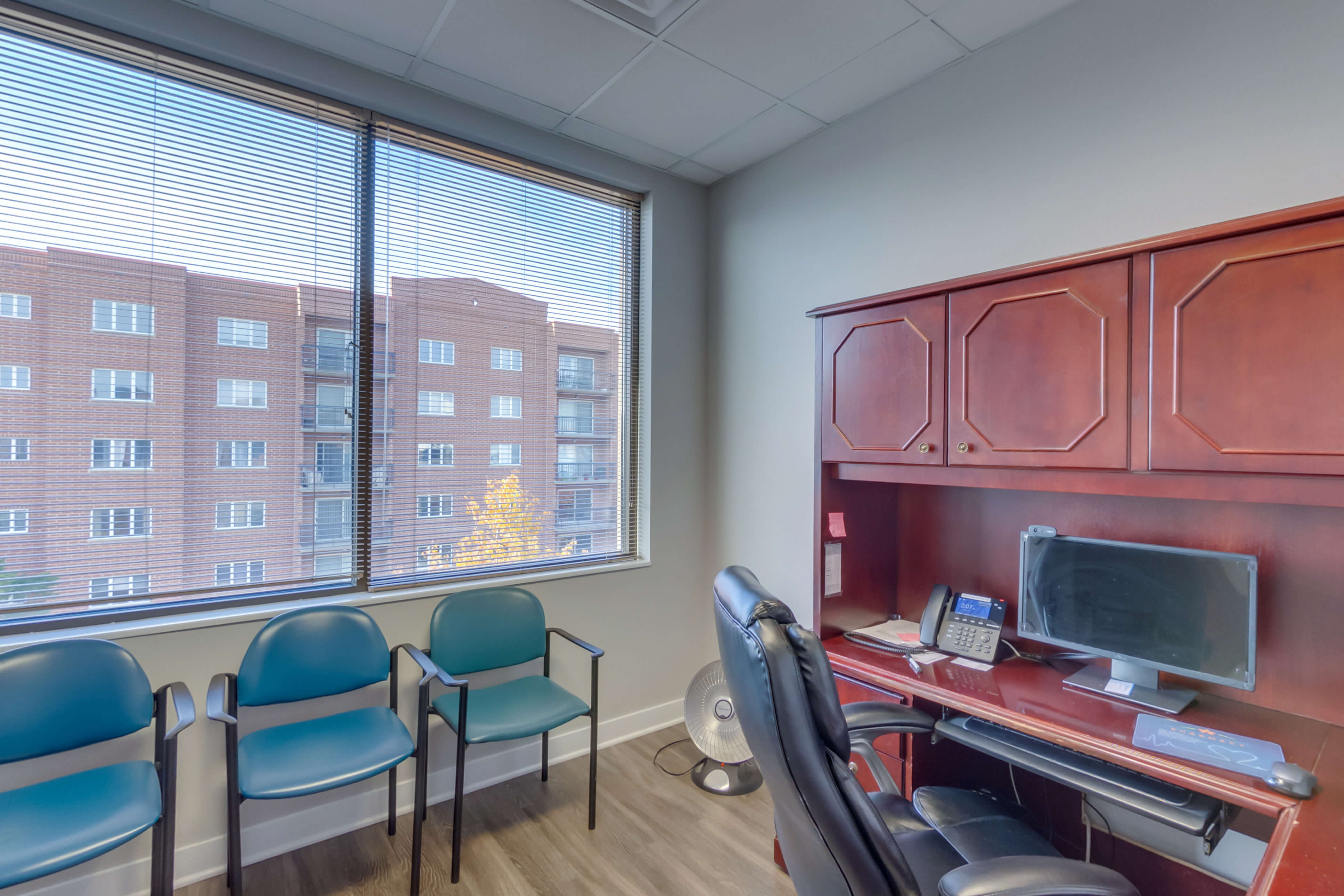 A small office with a desk, chairs, and a large window.