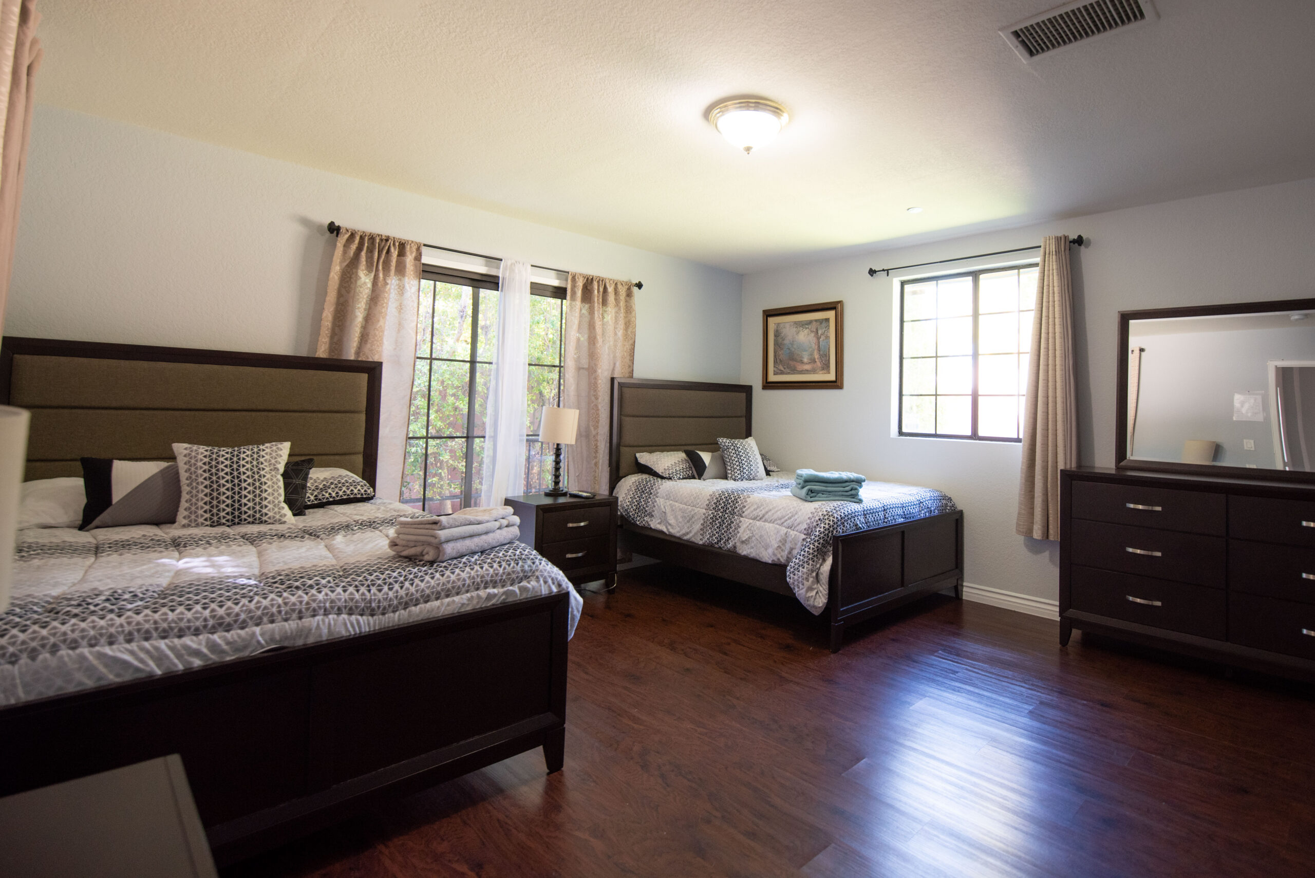 Shared bedroom with two beds, dresser, and natural light